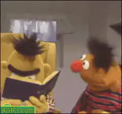 Bert reading a book while Ernie talks
