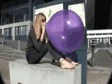 Woman blows up and pops a purple balloon