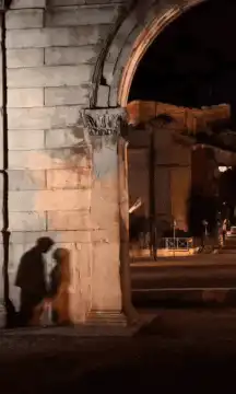 Couple kissing under archway at night