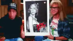 Two men holding a signed Pamela Anderson poster