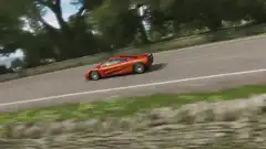 Orange McLaren F1 driving on a road