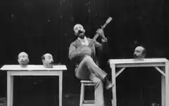 man playing guitar with singing heads
