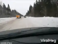 Car drifts past truck on snowy road