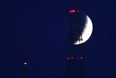 moon behind radio tower