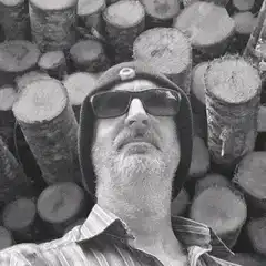 Man with glowing eyes in front of logs