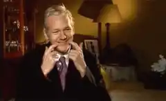 Julian Assange smiling and pointing
