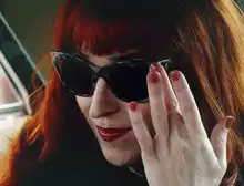 Woman lifts sunglasses to reveal eyes