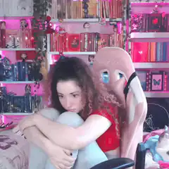 Sad girl hugging knees in pink room