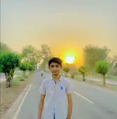Boy standing on road at sunset