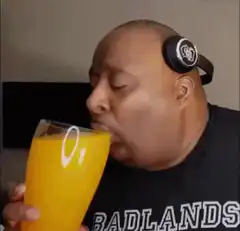 Man drinking orange juice with headphones