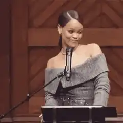 Rihanna plays with her hair at a podium