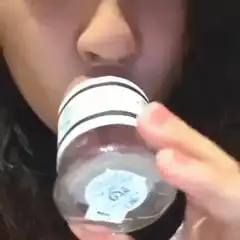 Woman drinks from bottle and licks lips