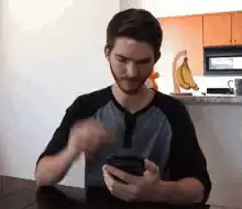 man scratching head looking at phone