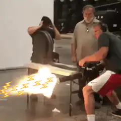 man fires flamethrower at another man