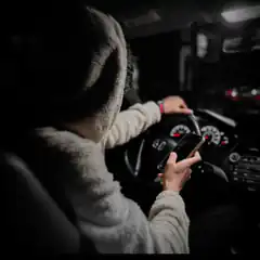 person driving at night looking at phone
