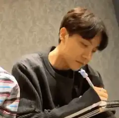 Man holding pen in mouth while writing