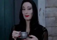 Anjelica Huston as Morticia Addams sipping tea