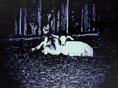 woman lying on ground with deer in woods