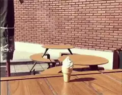 Woman eats ice cream cone off table
