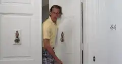 Man peeking out of door in yellow shirt