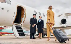 Businesswoman boarding private jet with crew