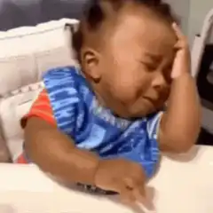 Baby crying with hand on forehead