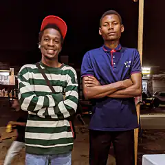 Two men standing with arms crossed at night