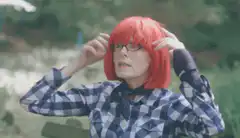 Woman adjusting red wig with caption
