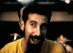 Man in yellow shirt smiling mischievously