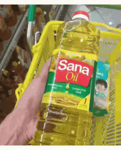 Hand holding Sana Oil bottle in shopping cart