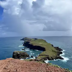 Green volcanic island peninsula with crashing waves