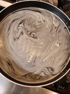 Swirling black and white liquid in a pan