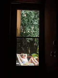 Woman relaxing on a patio seen through a window