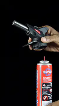hand igniting a butane torch