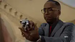 Man in suit aiming gun with intense look