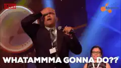 Man on stage facepalms with microphone