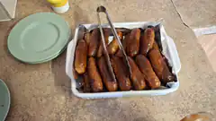 Baked sausages in baking dish with tongs