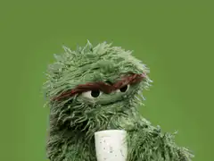 Oscar the Grouch drinks from a cup