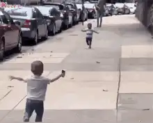 Two toddlers running to hug on sidewalk