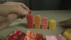 Hand stacking candy bars and picking M&Ms