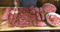Chef displaying various cuts of raw meat