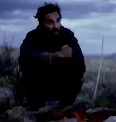 Man shivering by campfire