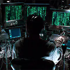 Person typing in front of green code screens