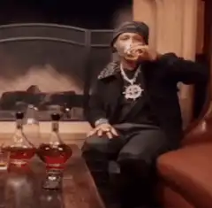 Man drinking liquor by fireplace