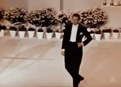 Man in tuxedo kneels and bows