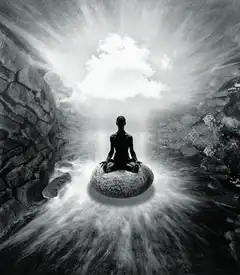 Silhouette meditating on a rock in a cave