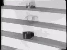 glass objects rolling down striped ramp
