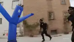 Blue inflatable man fights police