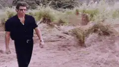 Man walks up to a large mound of dirt
