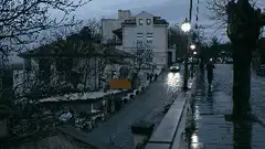 Car driving down wet street at night